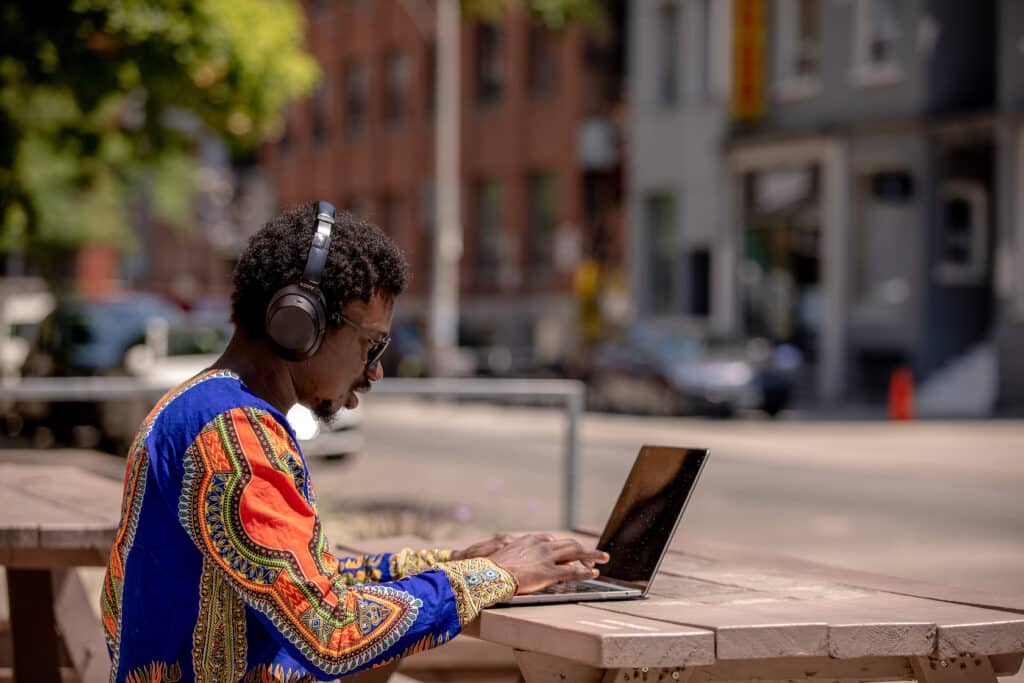 shopify team member working outdoors on laptop with headphones on