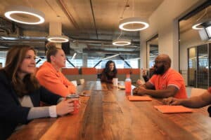 Avalara employees, wearing a lot of orange clothing to represent their company colors, enjoy a meeting.